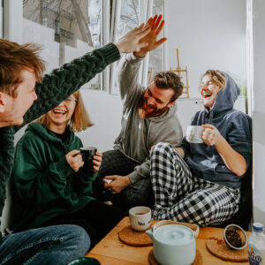 Group of friends laughing, two of which are high-fiving
